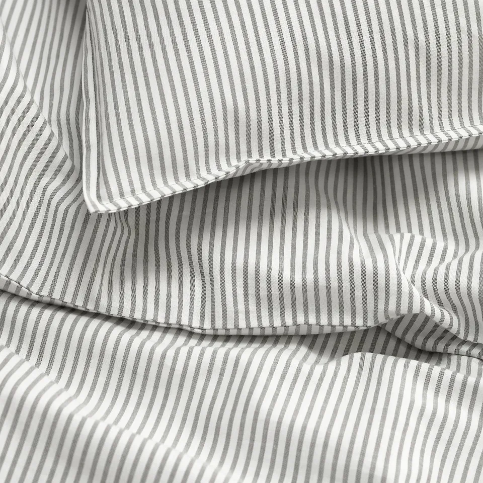Grayscale striped cotton fabric close-up, showing folds, texture, and stitching.