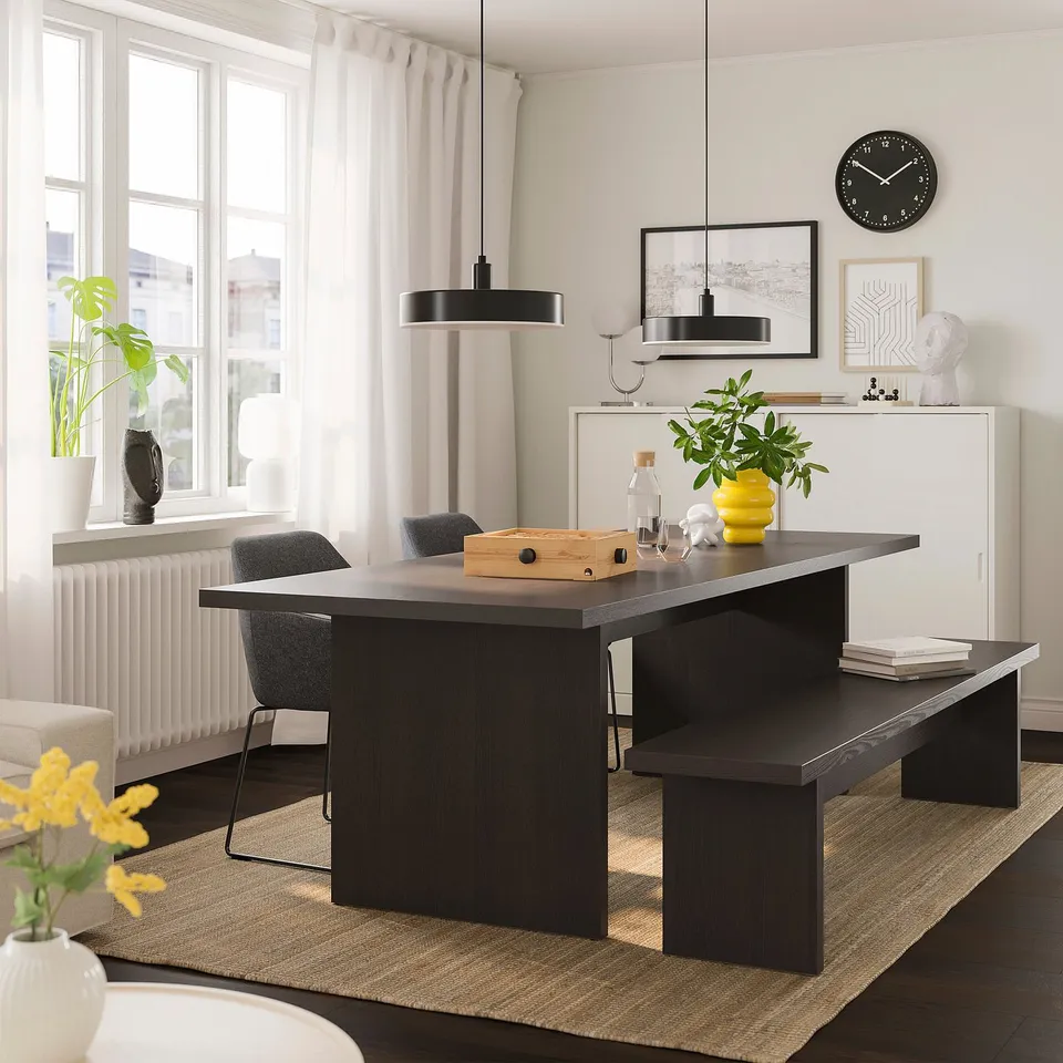Modern dining area with dark BERGSHYTTAN bench under matching table, grey chairs, and large clock against white wall.