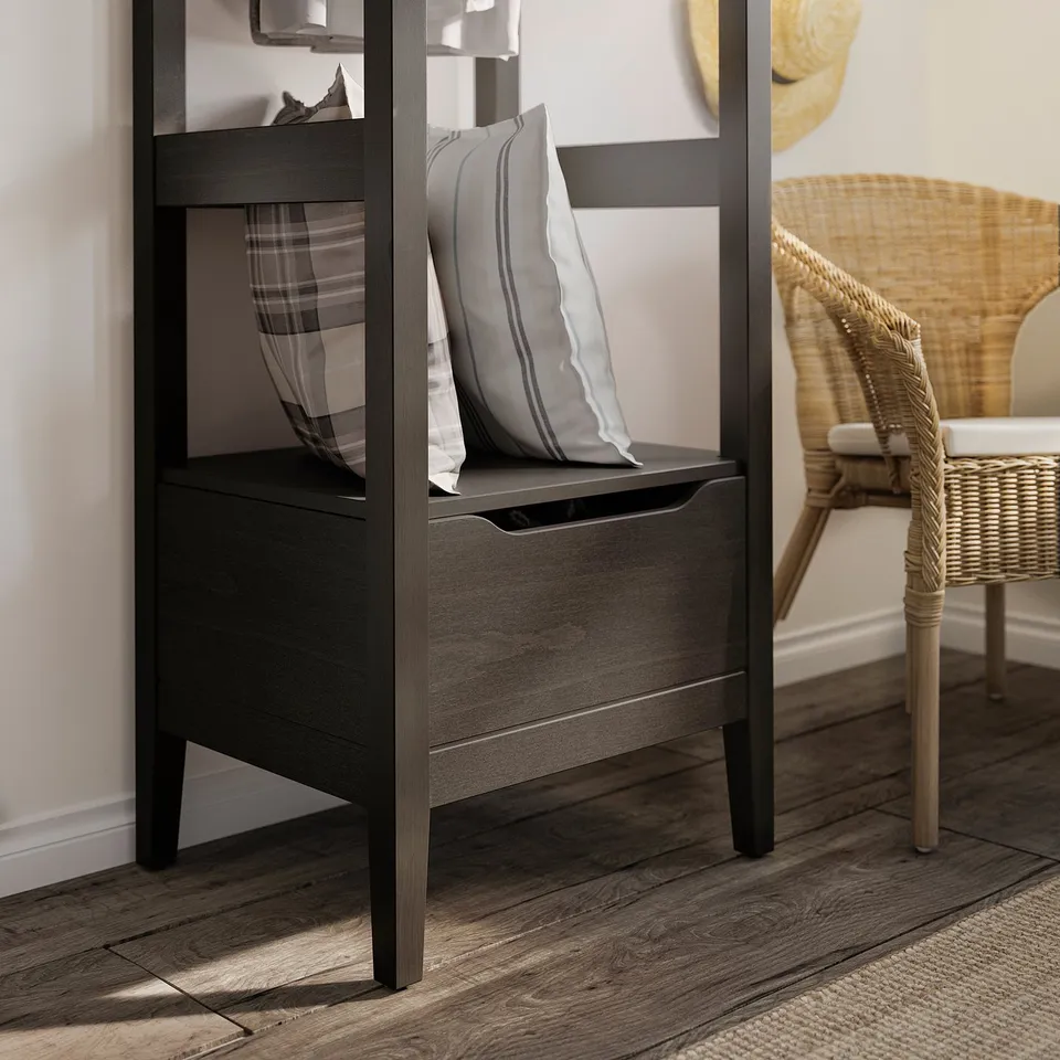 Black IDANÄS open wardrobe with striped pillow, wicker chair, wooden floor.