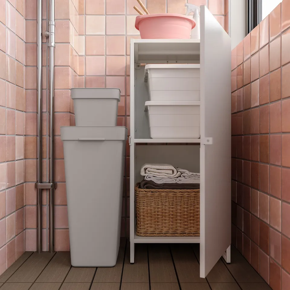 Grey JOSTEIN storage cabinet in bathroom with white bins and wicker basket.