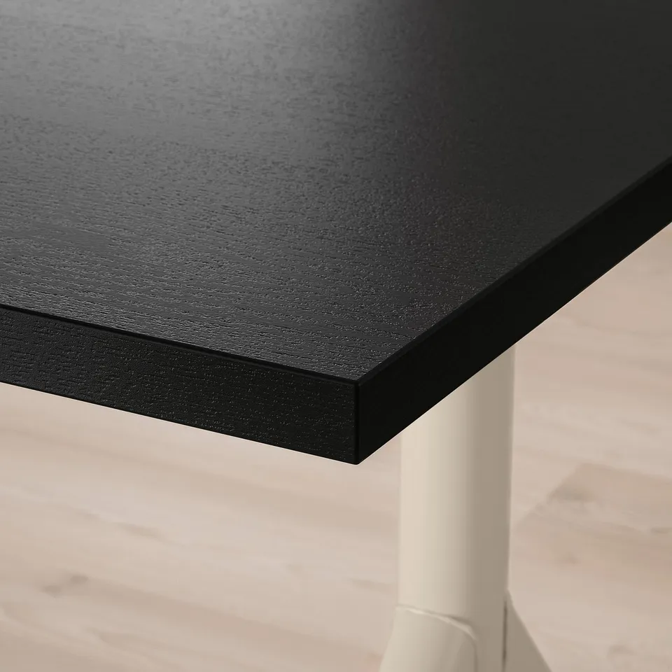 Close-up of stylish black desk edge, sleek surface and sturdy leg.