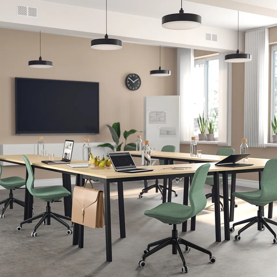 Modern conference room with green chairs, light tables, laptops, and large windows.