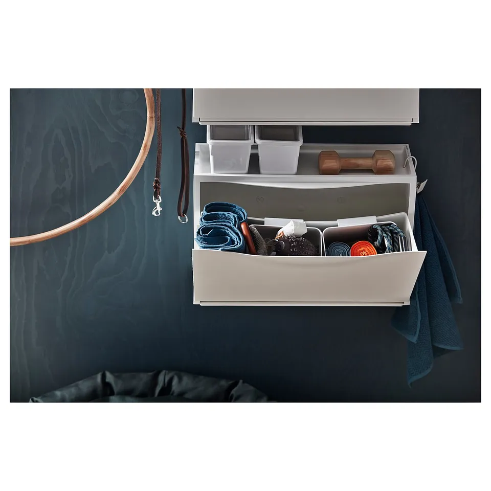 White TRONES storage cabinet with various items inside and out.