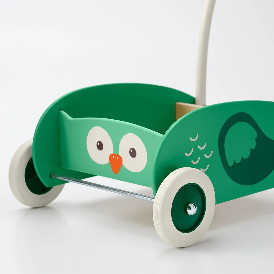 Childs wooden walker with green owl design, large eyes, orange beak, and four wheels for safe learning.