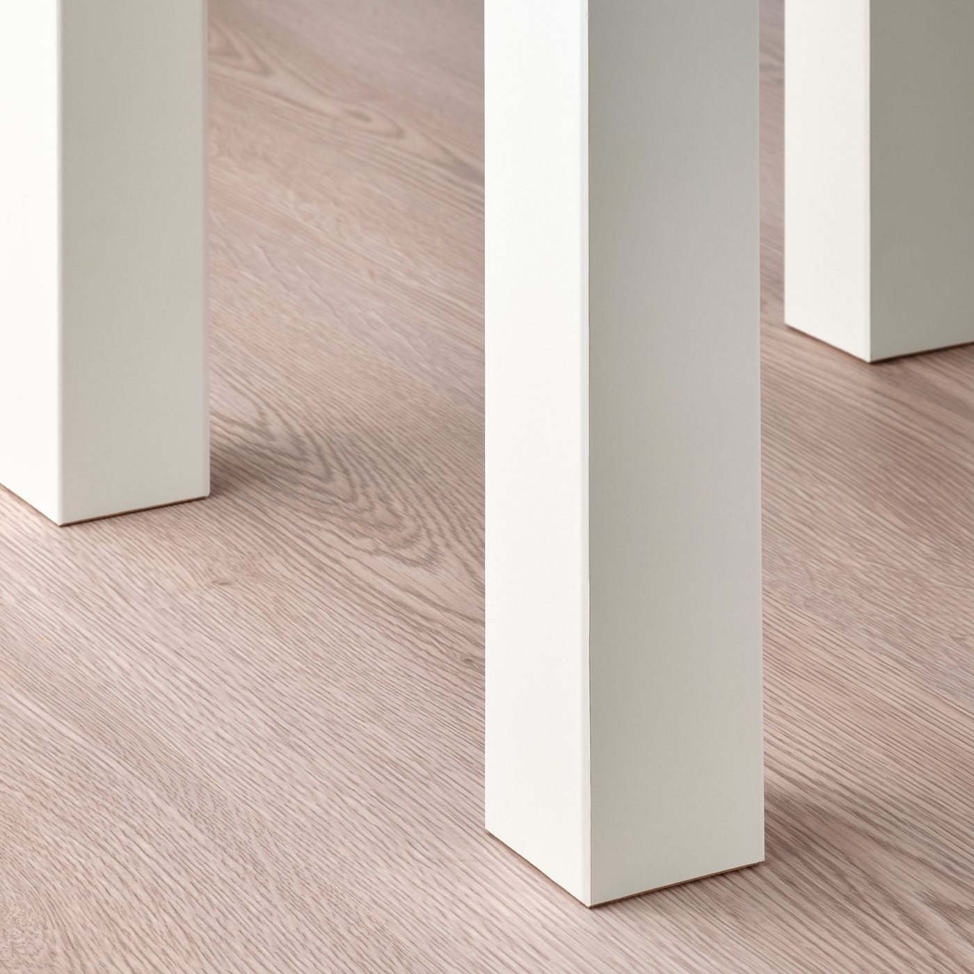 Three white LACK tables on light wooden floor, neatly arranged, showcasing clean design and sturdy build quality.