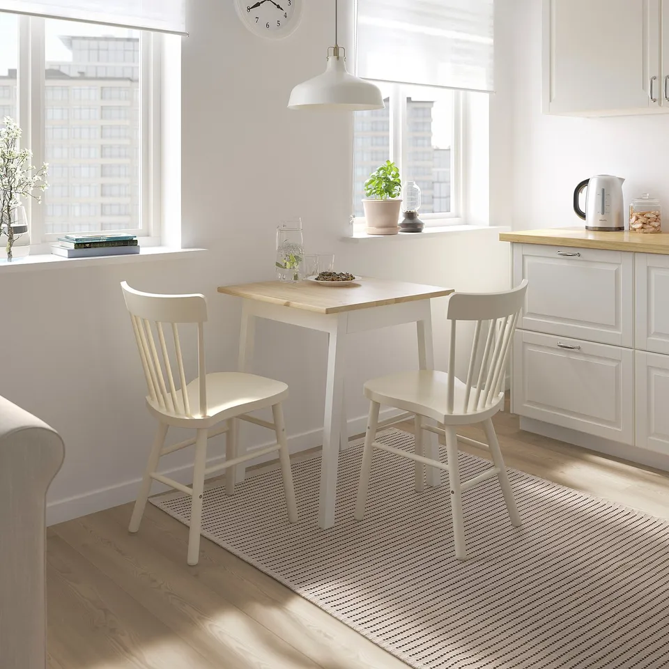 Kitchen with light table, chairs, & black/white striped rug, enhancing style & comfort.