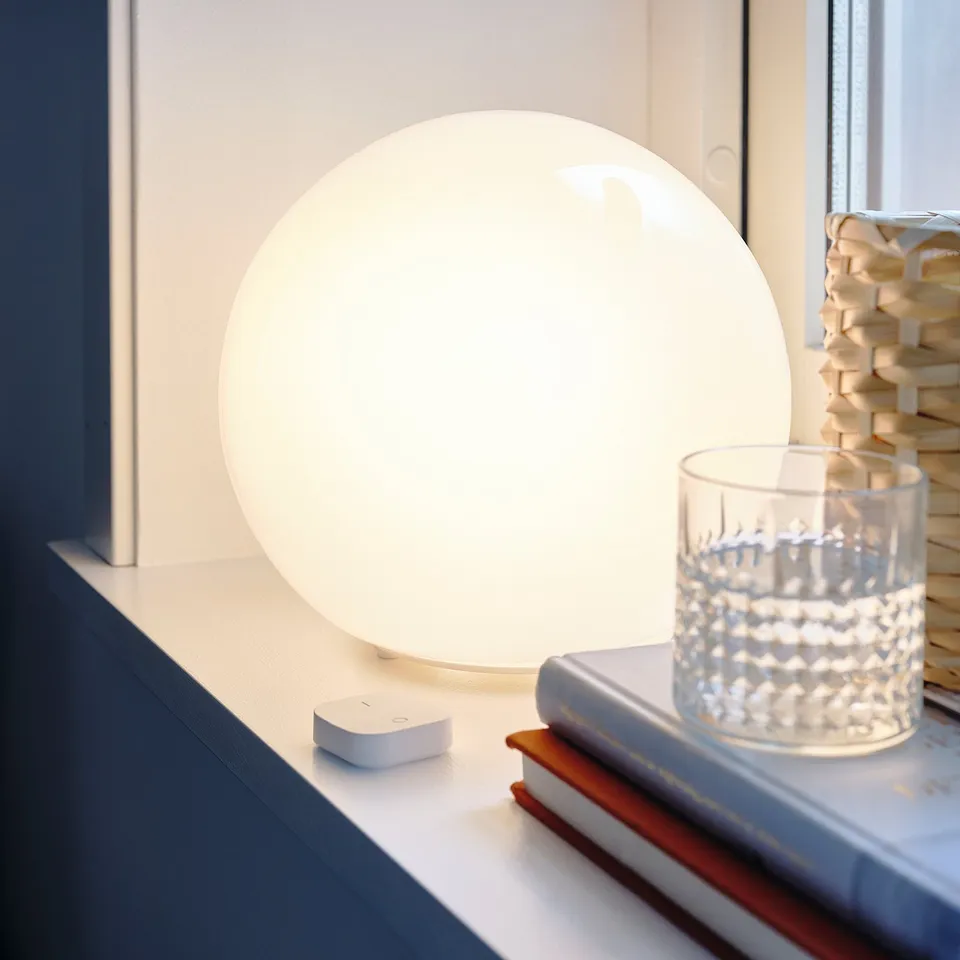 FADO lamp, white globe glass on stand, beside books and candle holder.
