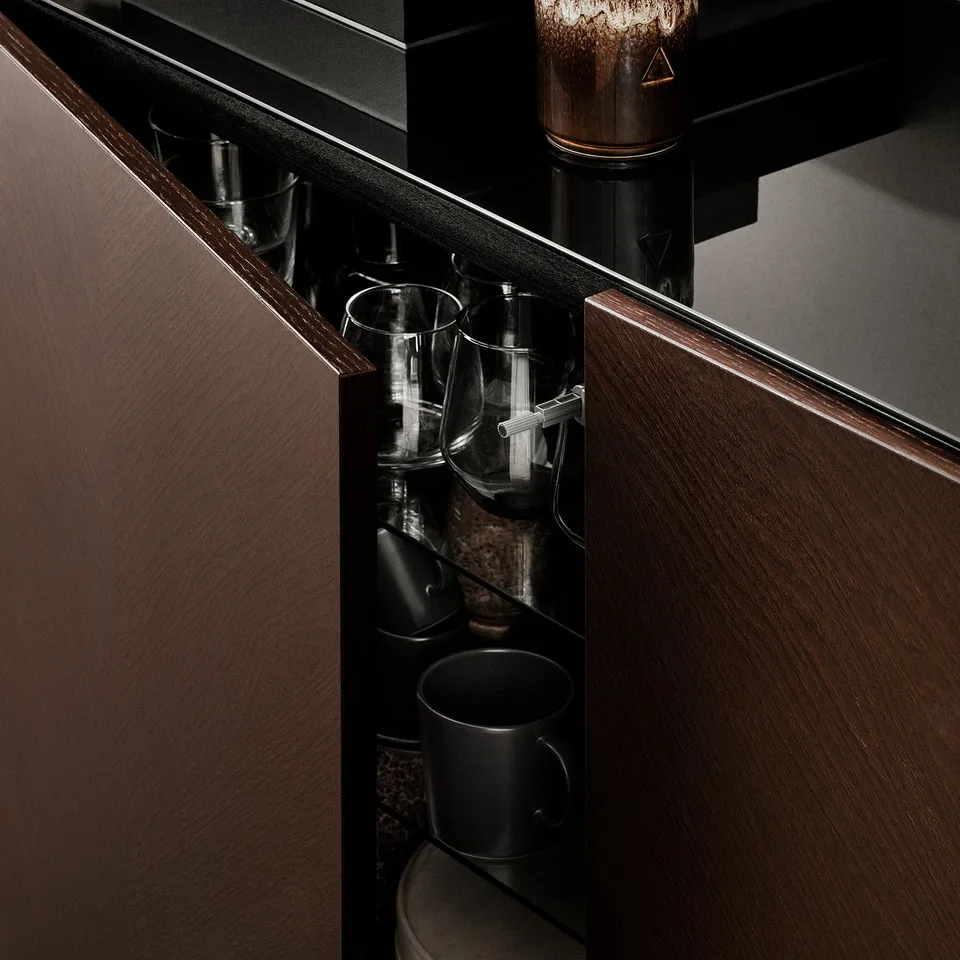 Dark wood cabinet with shelves holding black mugs and clear glasses.