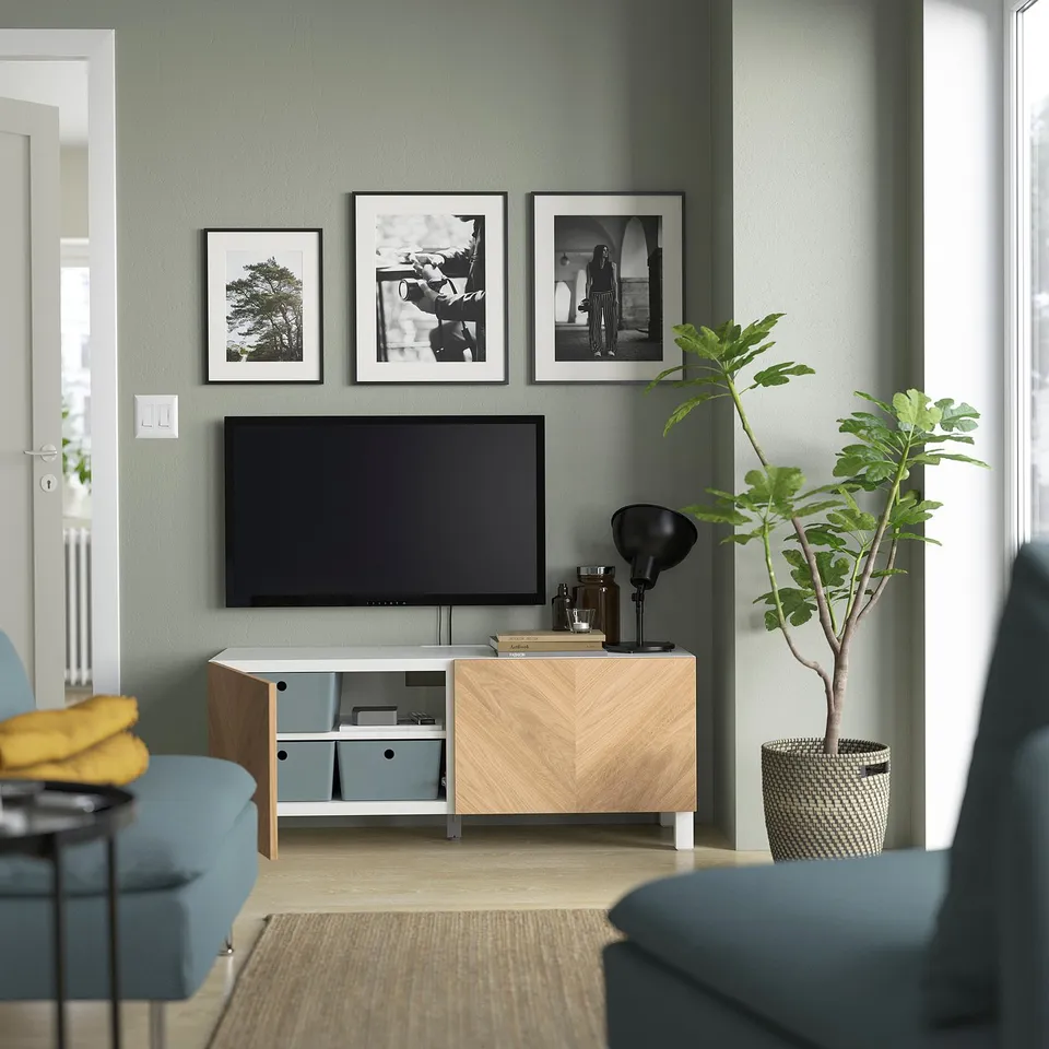 Modern living room with BESTÅ unit, tv, plant & blue sofa.