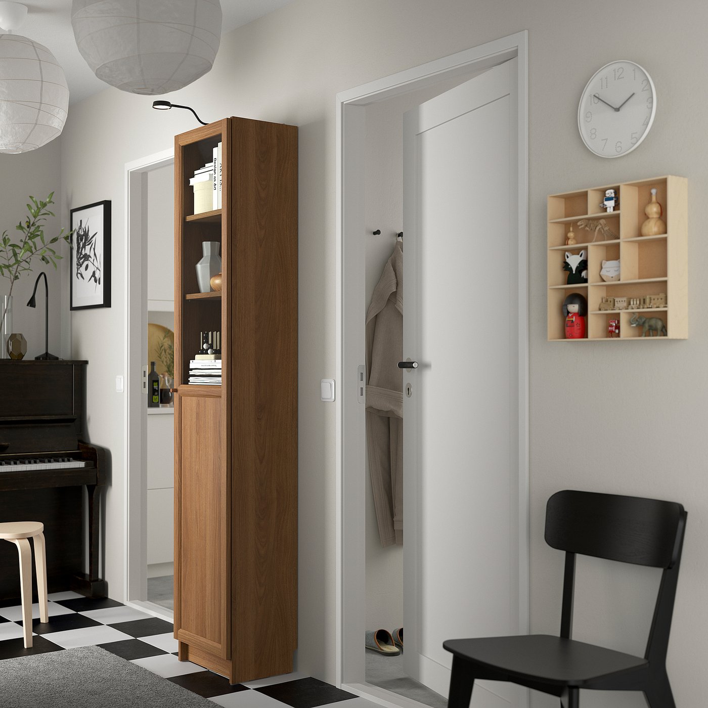 Modern living area with BILLY bookcase, piano, and chair. Bookcase has glass doors, clock, and wall shelves.
