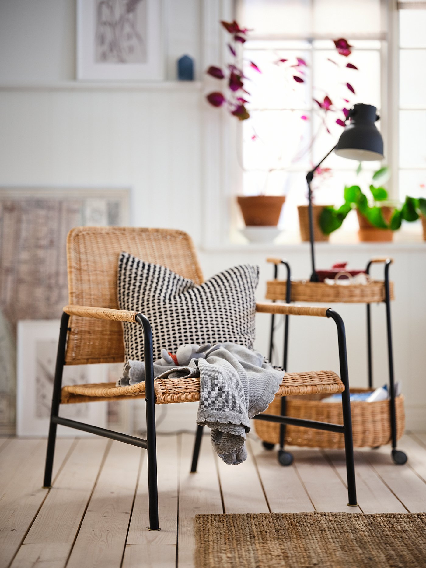 Cosy living room with ULRIKSBERG wicker chair, lamp cart, and plants.