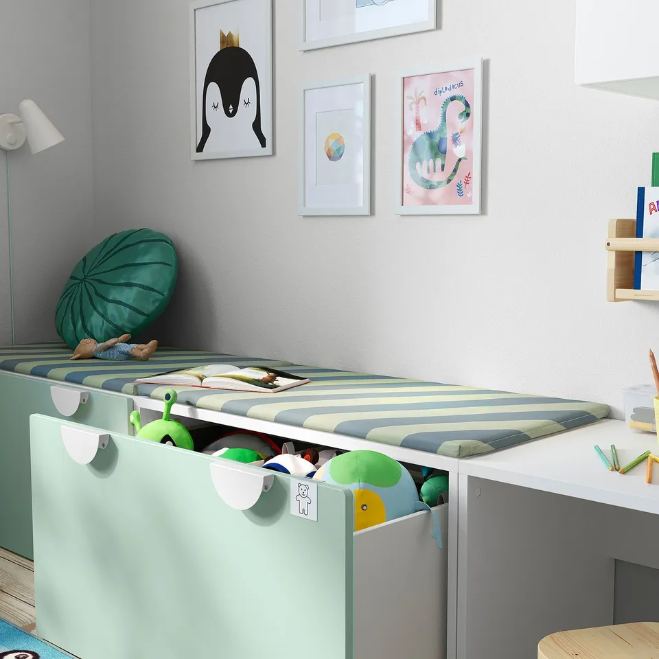 A childrens bedroom featuring a SMÅSTAD storage bench, organising toys and books, with striped bedding and colourful wall art.