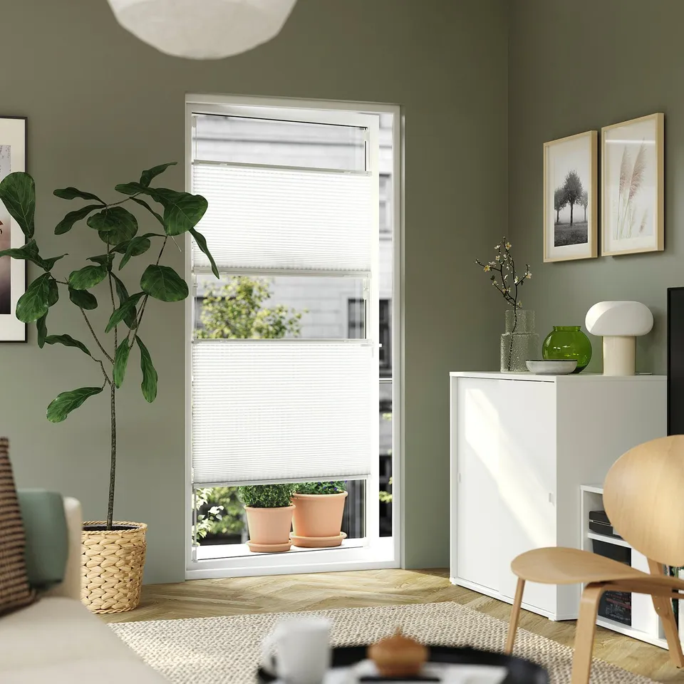 Minimalist office with HORNVALLMO blind, plant, desk, lamp, flowers, art, chair, rug.