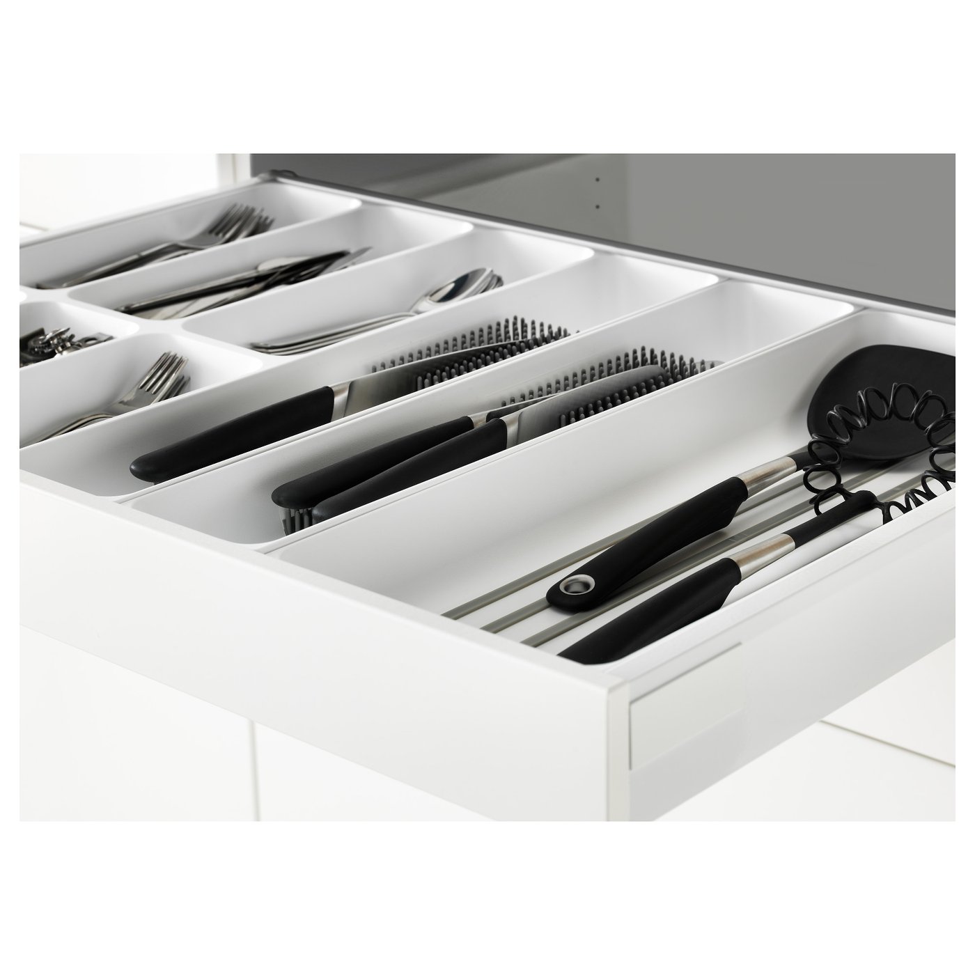 Open kitchen drawer with organised utensils: forks, spoons, knives, and cooking tools, showcasing white interior and black-handled items.