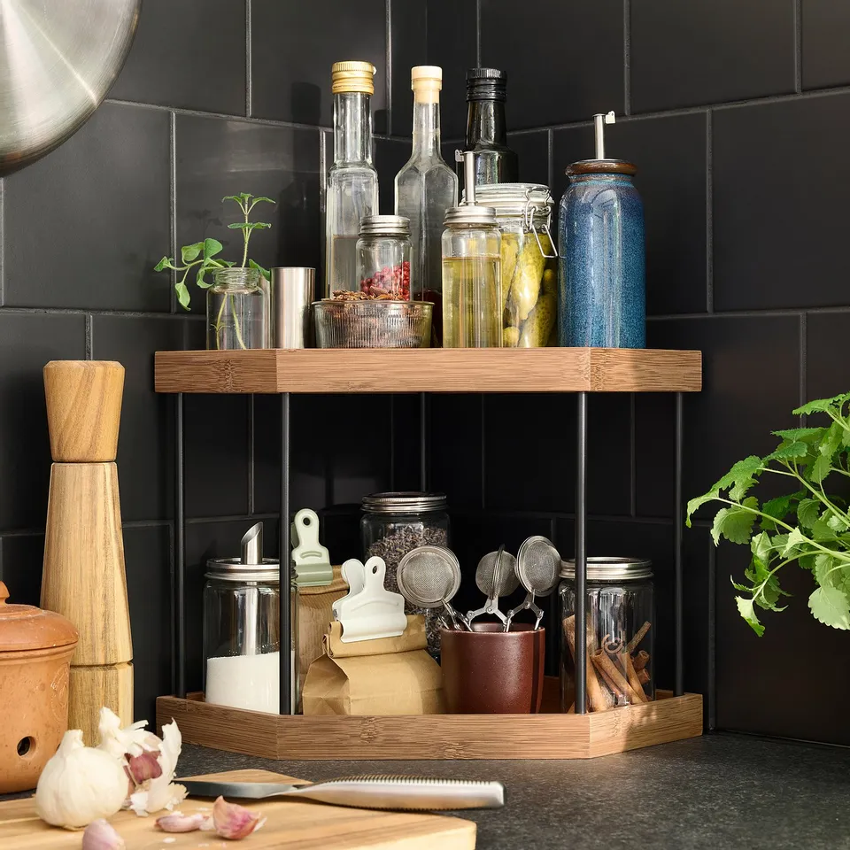 Wooden corner kitchen organiser with adjustable shelves, storing jars, bottles, and herbs.