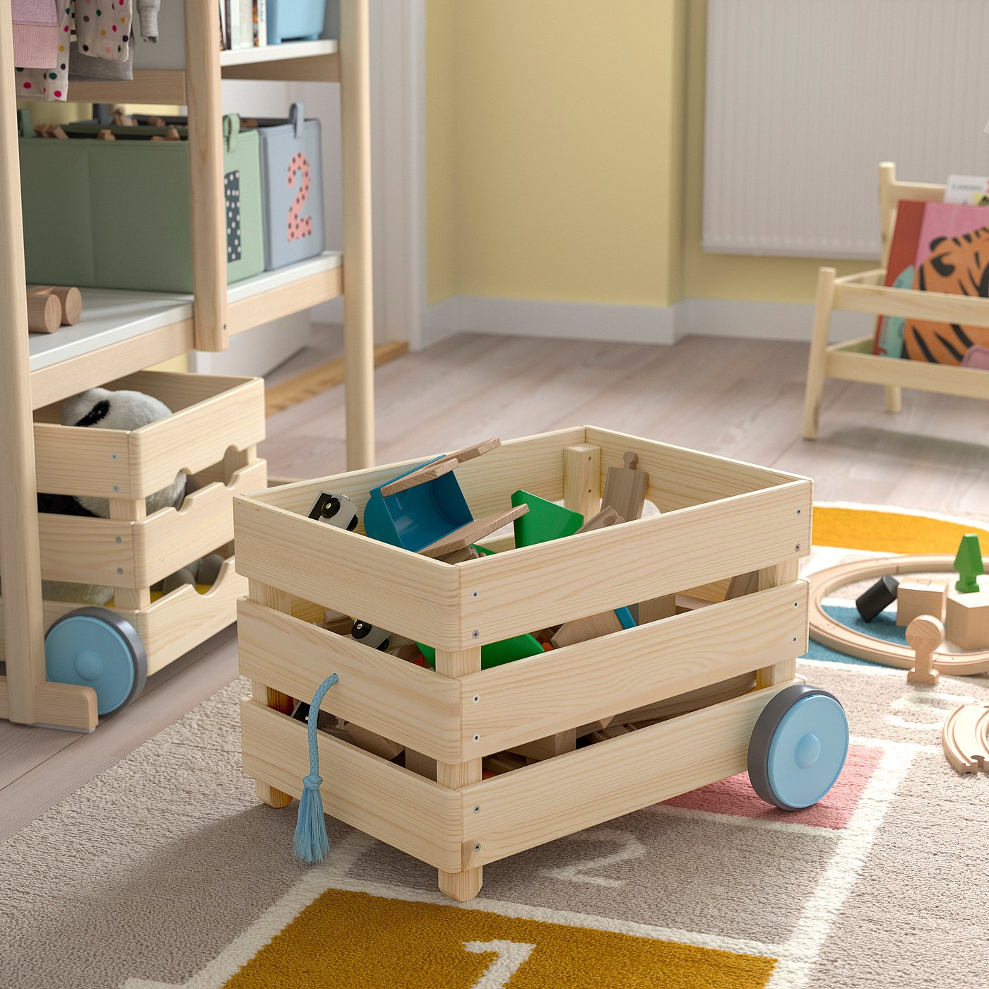 Wooden toy storage cart with wheels, containing colourful childrens toys, ideal for easy transport and organisation in a playful room.