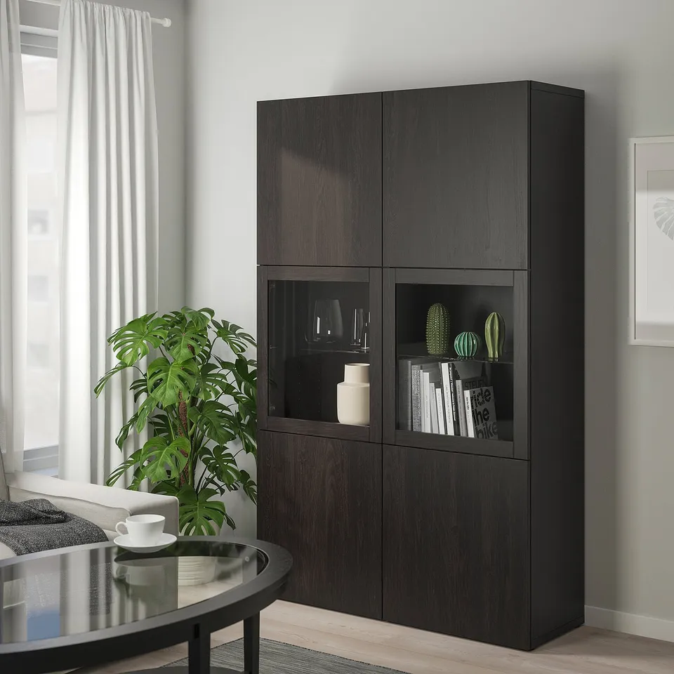 Black BESTÅ cabinet with glass doors for dust-free display, beside a window, black coffee table, and plant.