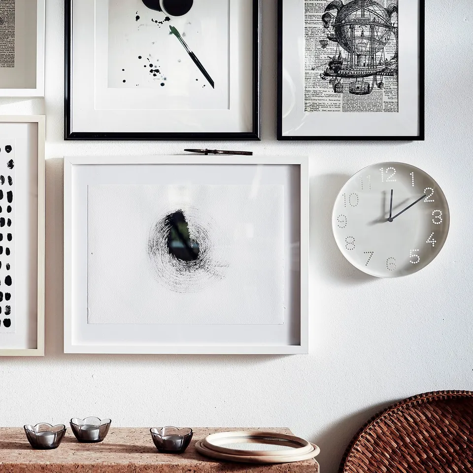 Modern clock with white face and black hands, art, nautical-themed table setup.
