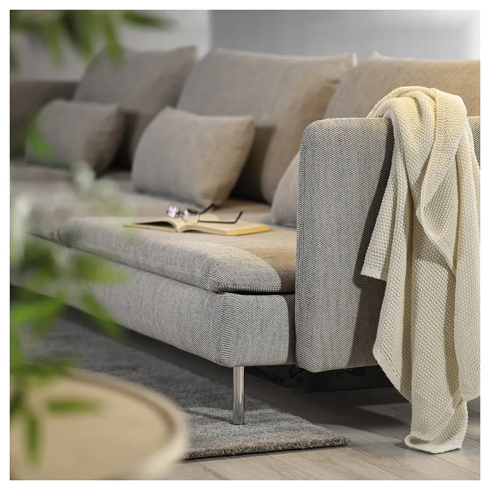 Beige SÖDERHAMN sofa bed with cushions, blanket, and book.