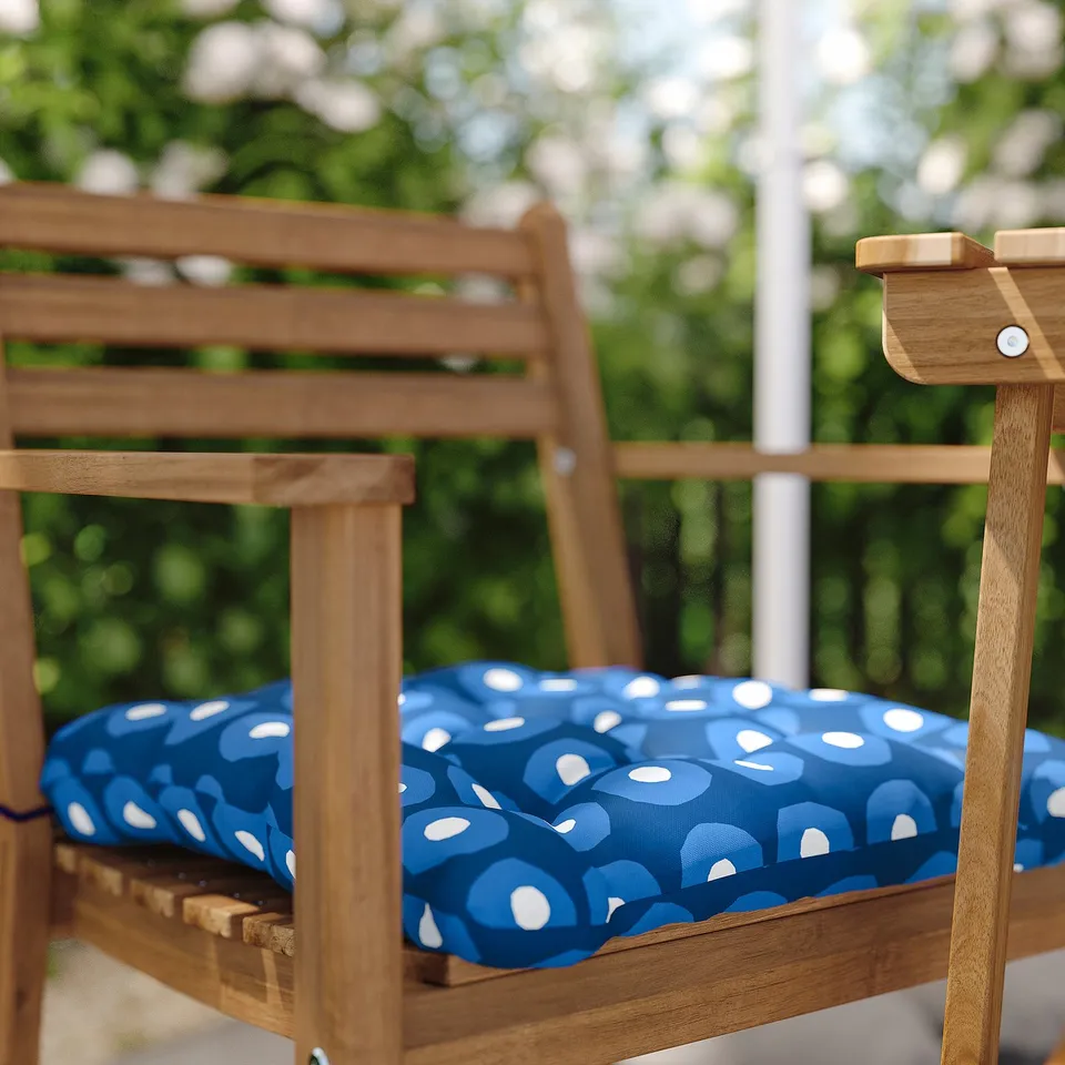Wooden outdoor chair with blue patterned cushion.