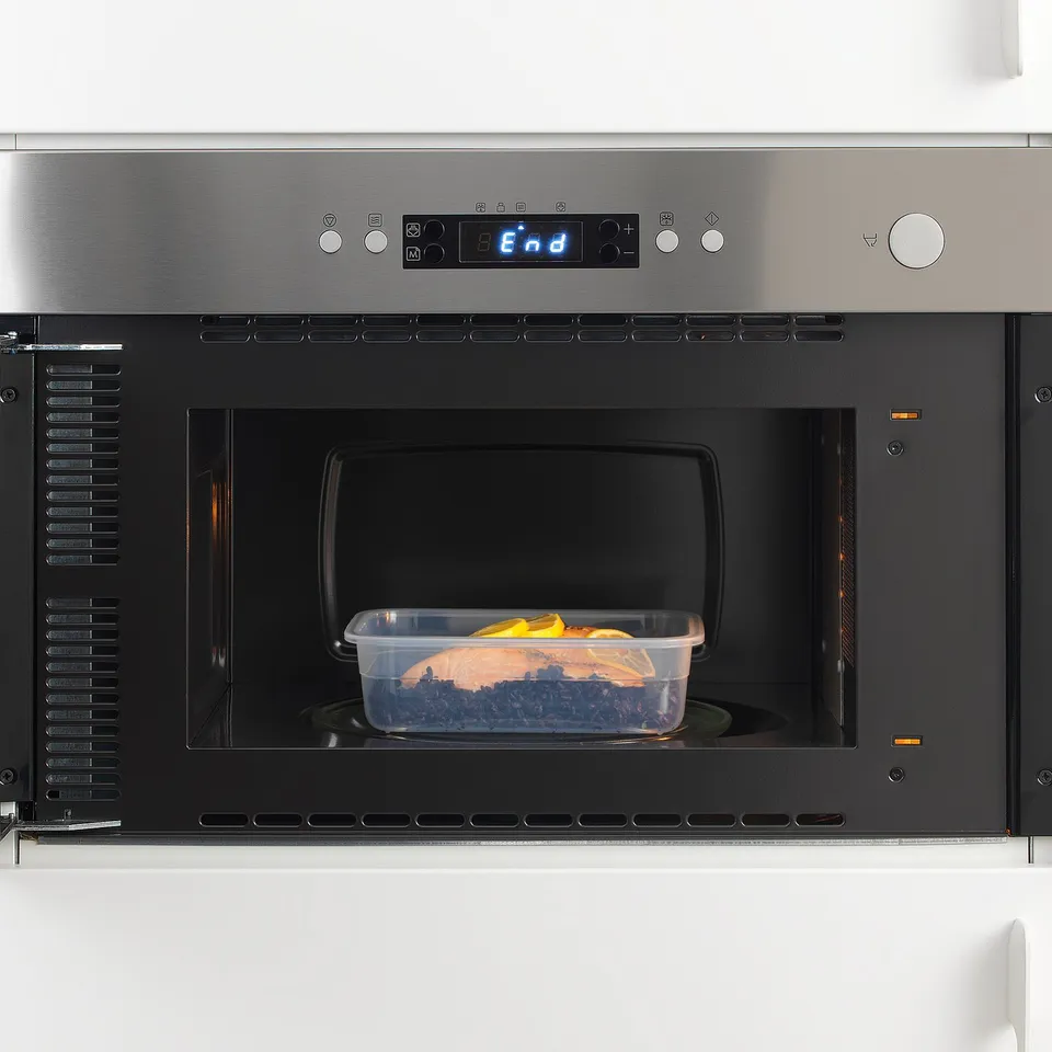A modern microwave oven with food in it. Digital display shows end, its stainless steel framed.