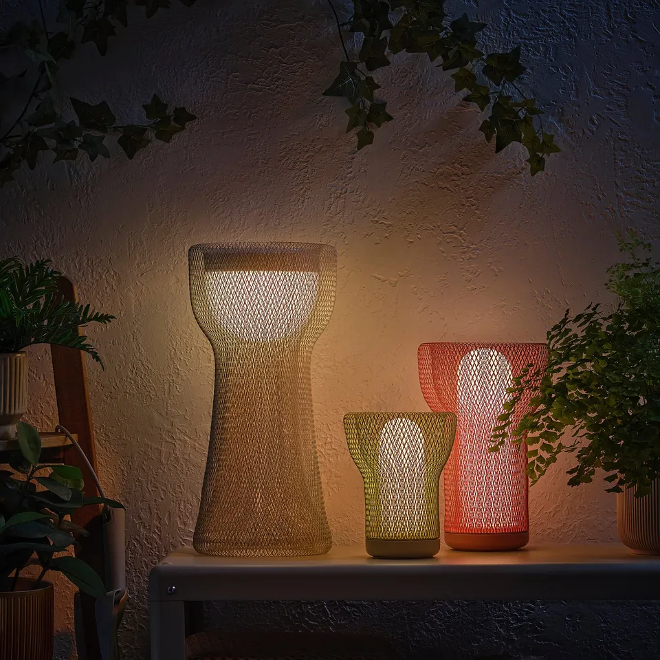 Three decorative lights on a shelf, lit with plants.
