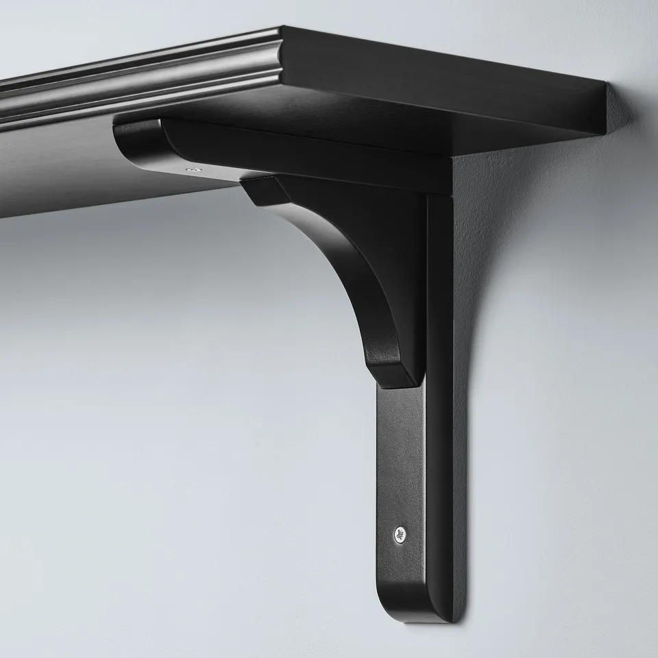 Black wall-mounted shelf with a stylish bevelled edge, securely attached with a robust metal bracket, mounted on a smooth, light-colored wall.