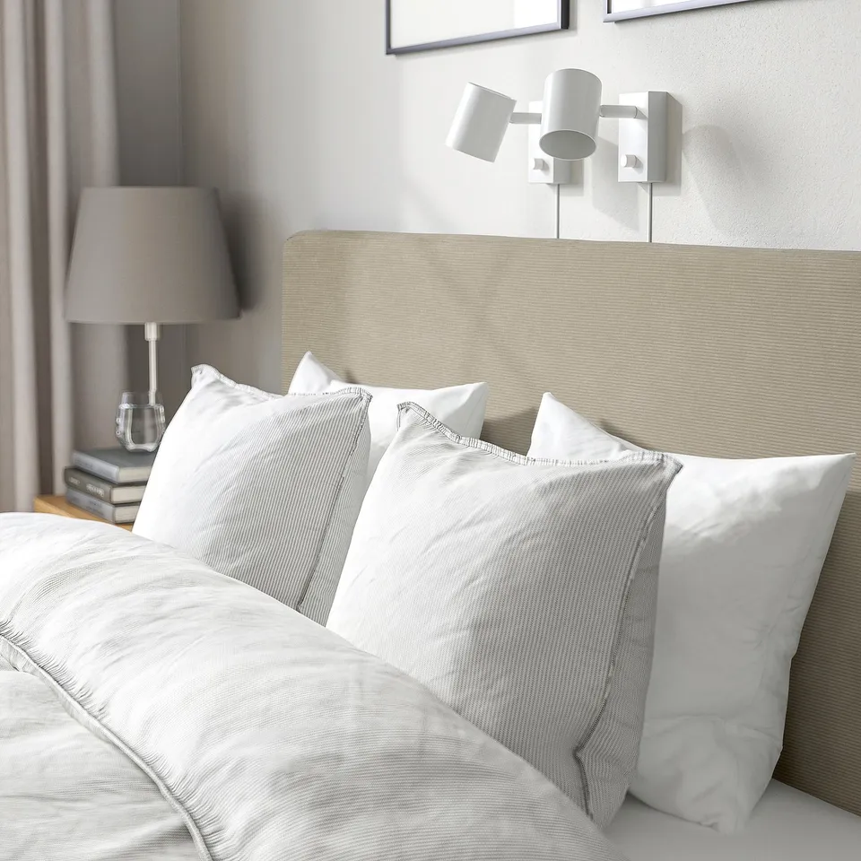 Modern bed with padded headboard, wall lights, and decorative cover.