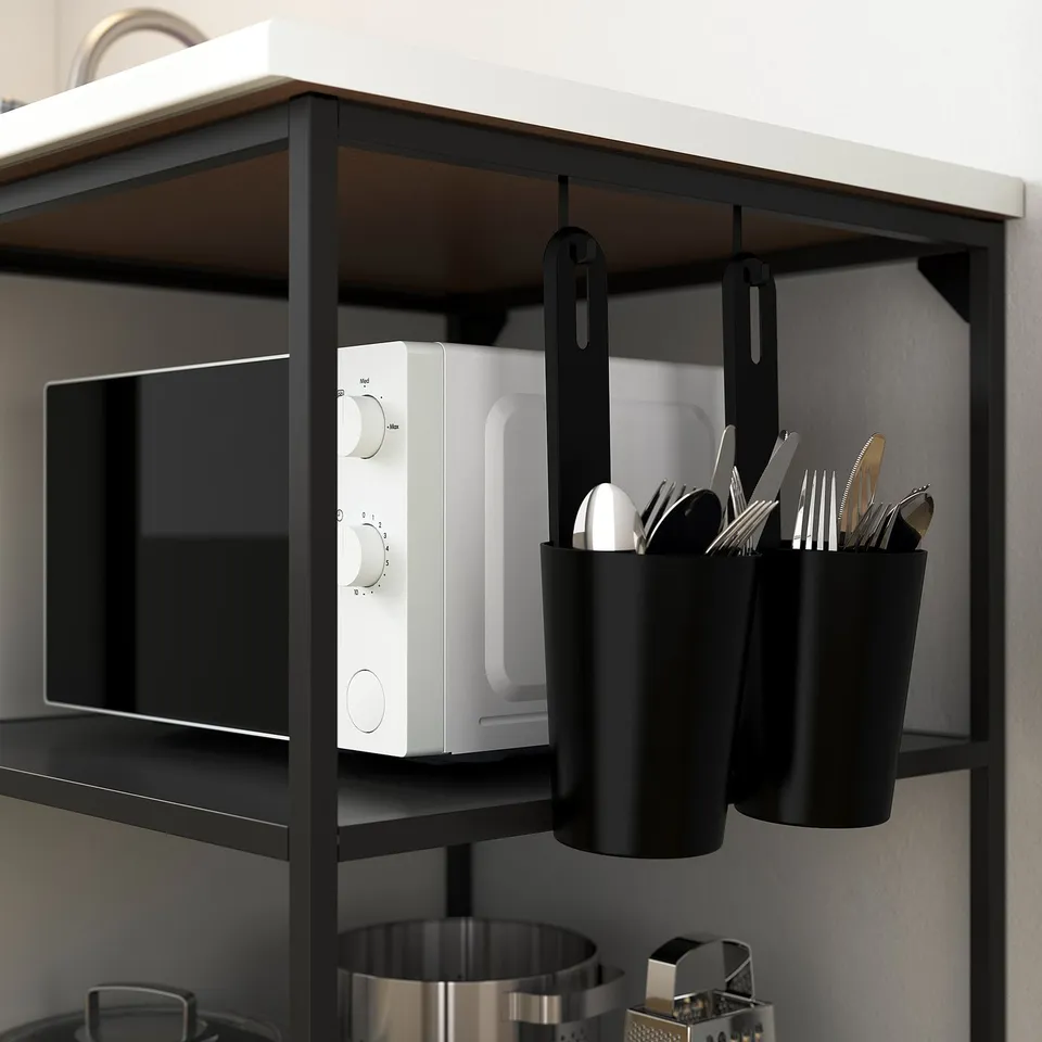 Image shows kitchen shelving with hooks holding containers and a microwave. The containers hold utensils.