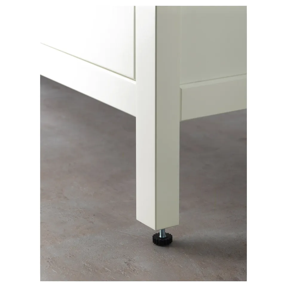 Close-up of white cabinets bottom drawer with soft-close mechanism and floor leveller.