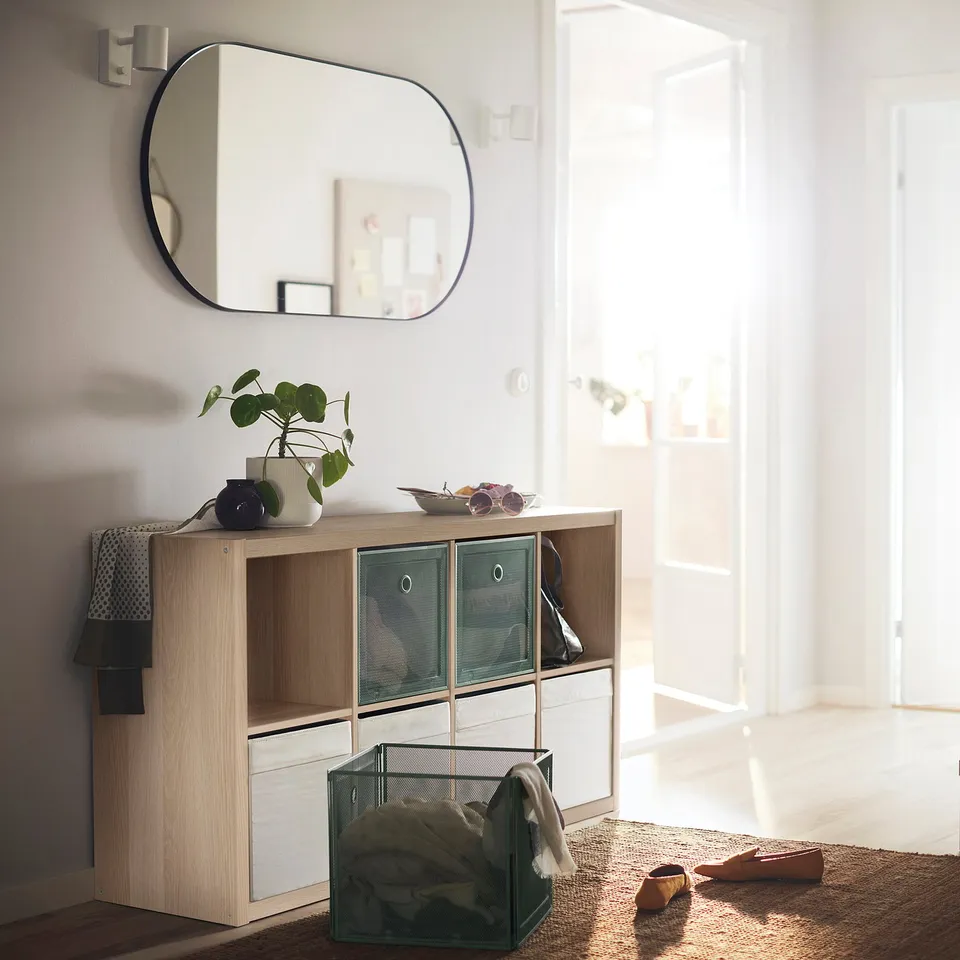 KALLAX shelving with mesh drawers, plants, mirror in bright room.