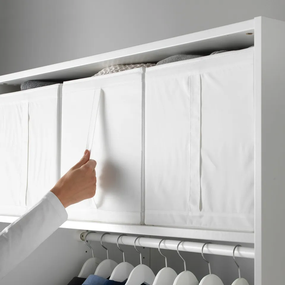 Person opening white SKUBB storage box in wardrobe, showcasing its handle and organised compartments.
