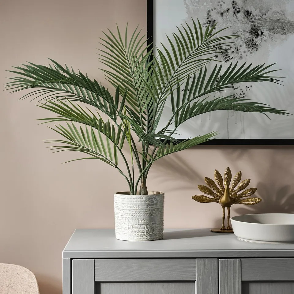 White potted palm on grey sideboard with gold decor.