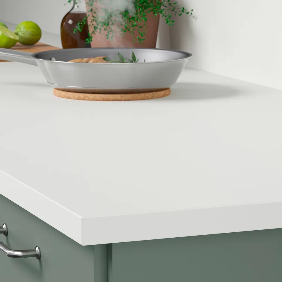 White kitchen countertop with grey frying pan containing food; part of modern kitchen setup.