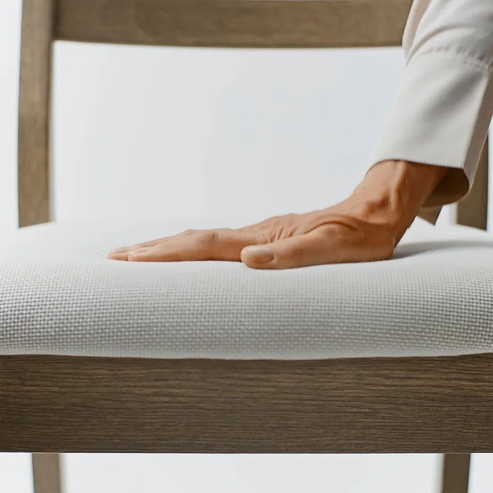 Hand resting on TONSTADs soft, premium textured chair. Solid wood, sturdy, quality evident.