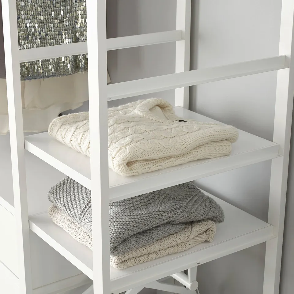 Folded white blankets neatly organised on white wooden shelves.