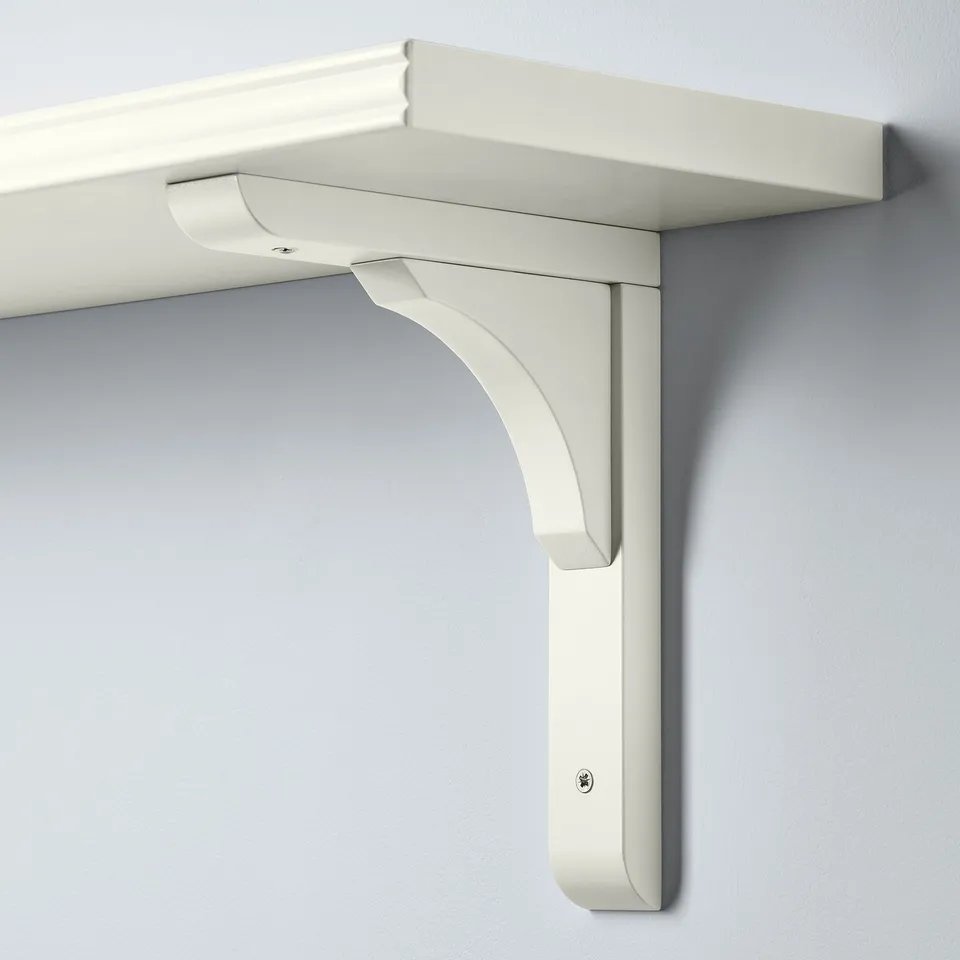 Wall-mounted shelf with smooth and bevelled edges, supported by a curved bracket. White colour, clean design.