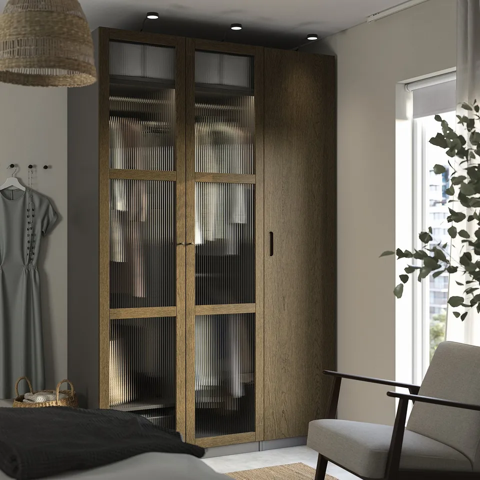 Modern bedroom with large TONSTAD wooden closet, grey chair, and potted plant.