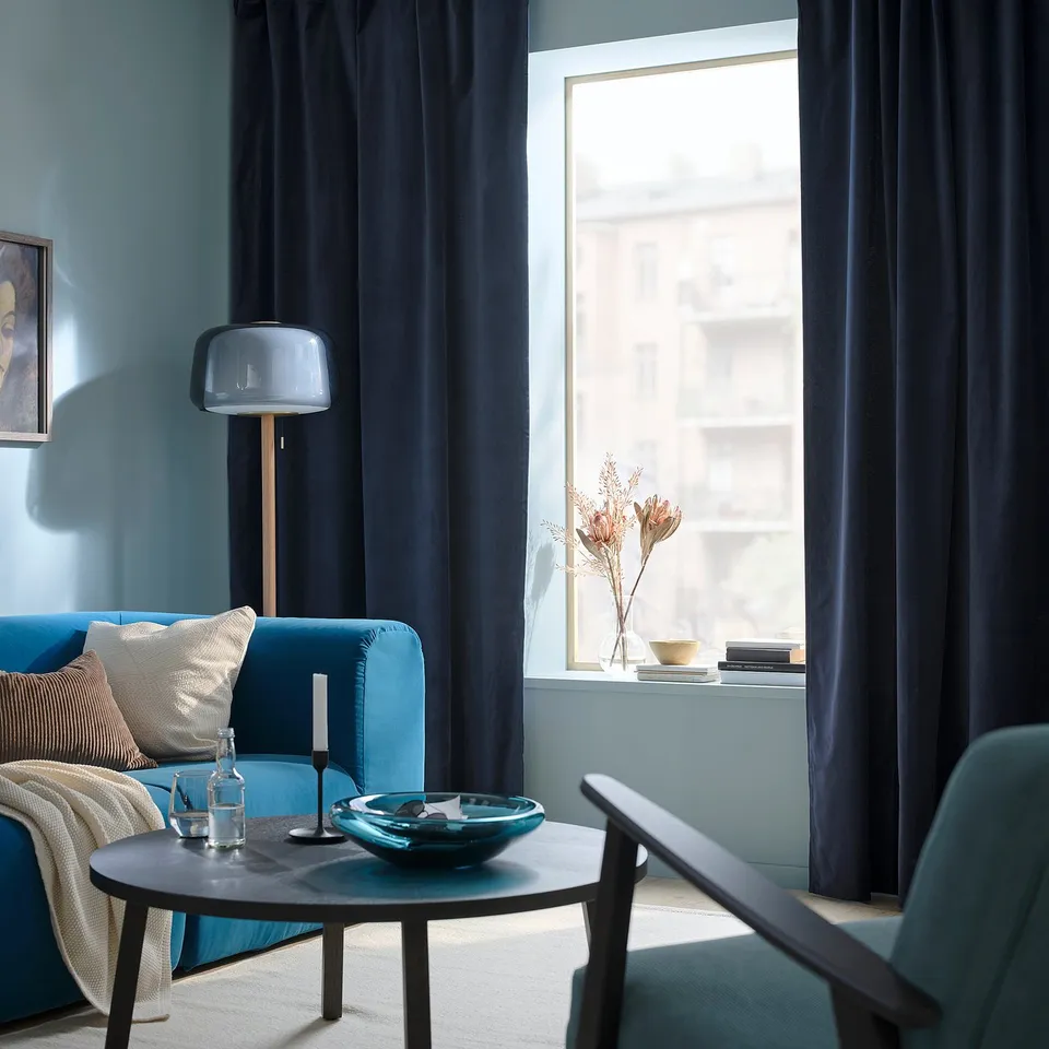 Modern living room with dark blue curtains, turquoise sofa, and round coffee table.