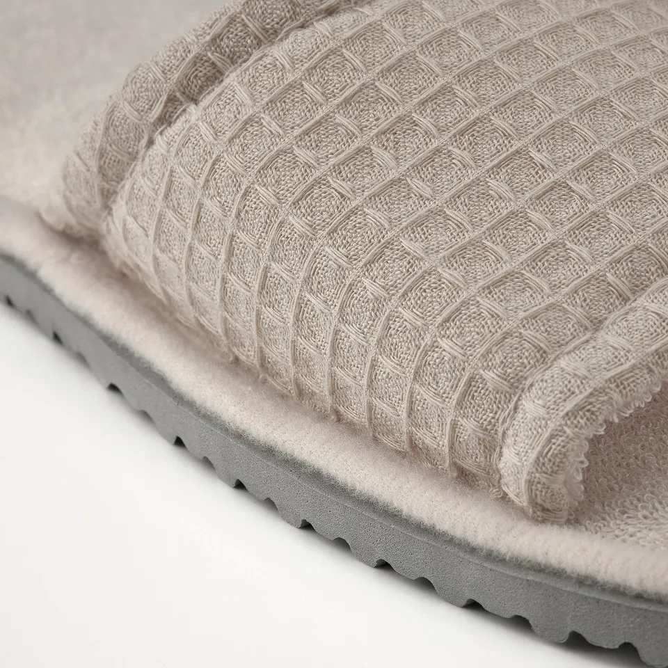 Beige slipper with soft, cushioned sole and waffle-textured top.