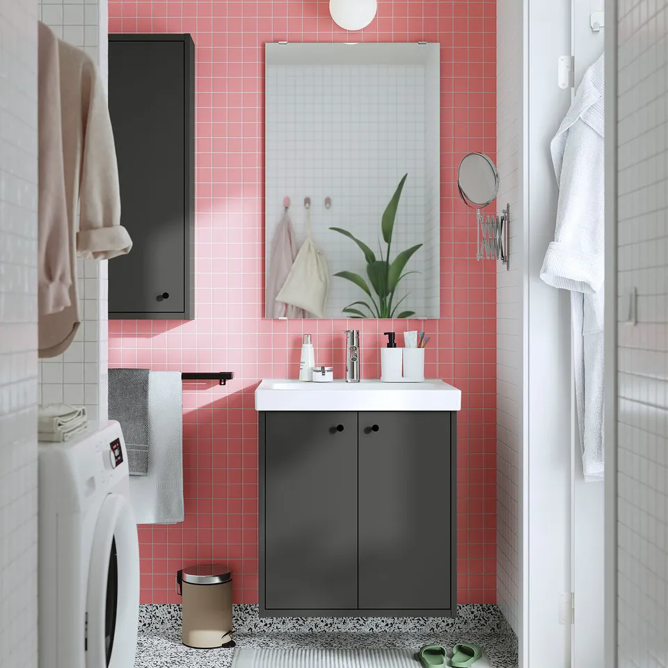 Modern bathroom with black HAVBÄCK vanity, red tiles, white sink, mirror, and plant.