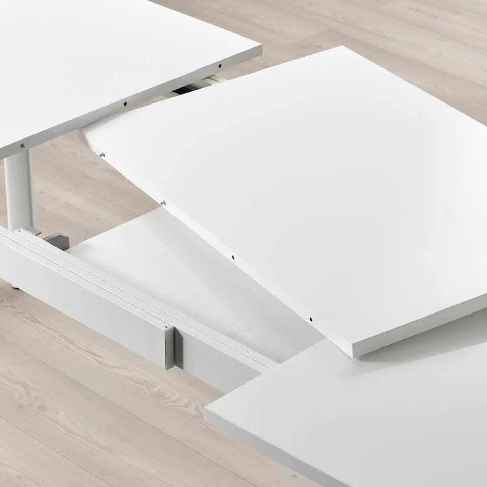 White extendable table with two leaves tucked underneath.