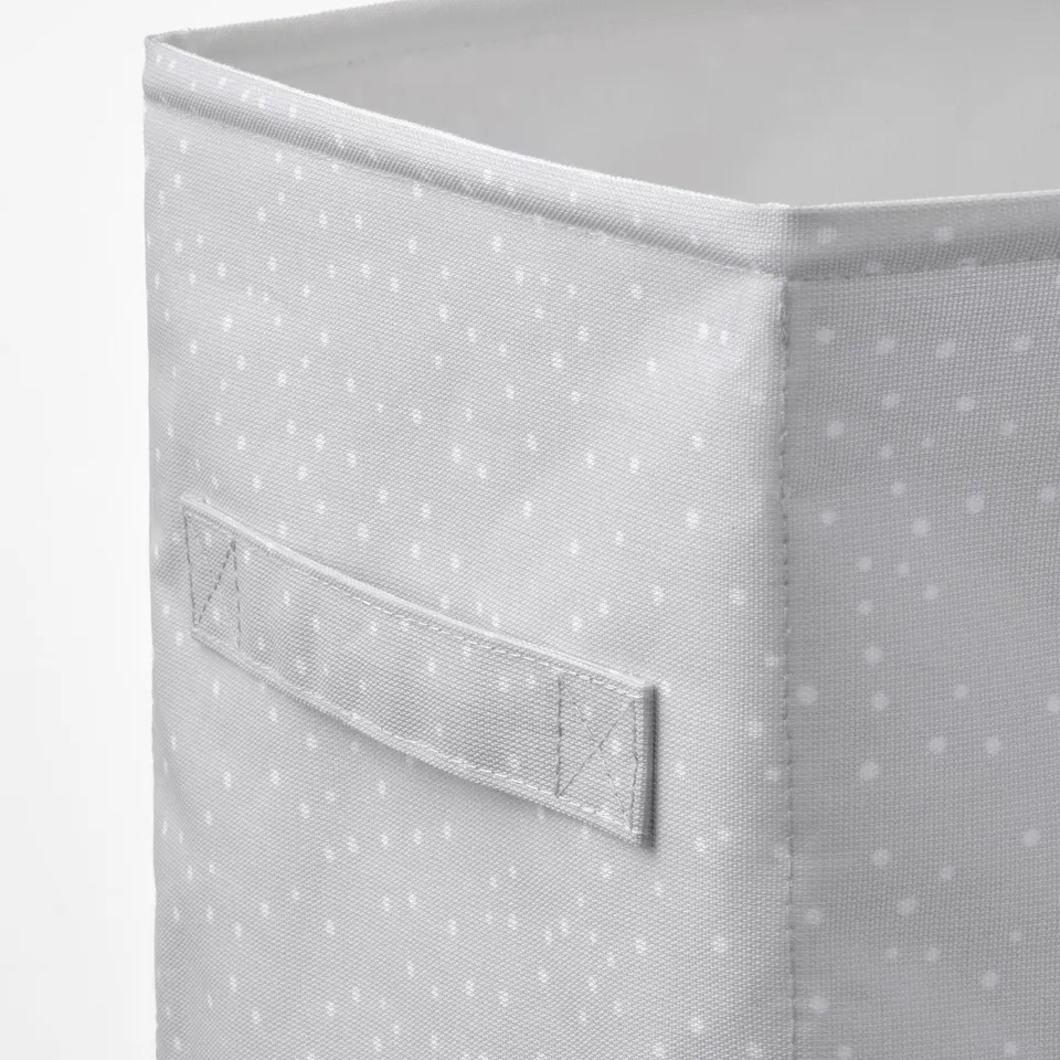 Close-up of a light grey fabric storage box with small white dots. A handy front pocket secured by velcro.