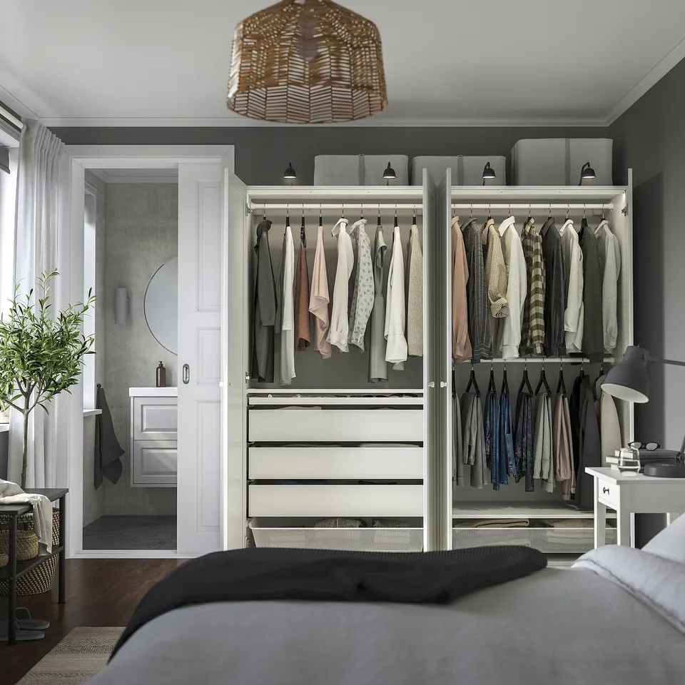 Modern bedroom with open wardrobe showing clothes storage, drawers, and integrated lighting.