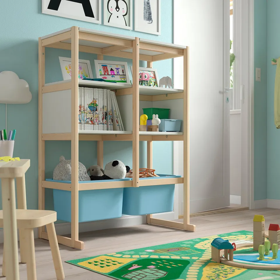 Kids room with light wood FLISAT shelves, blue bins, toys, books, and chairs.