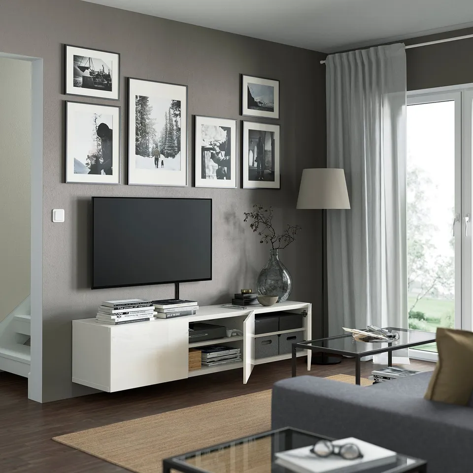 Modern living room with wall-mounted tv stand, decorative photos, glass coffee table, and floor lamp.