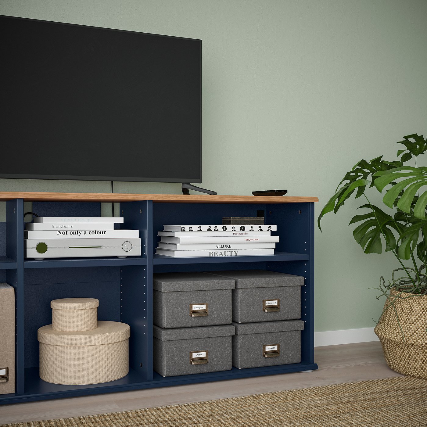 Modern tv stand with shelves and storage boxes, holding books and a flat screen tv.