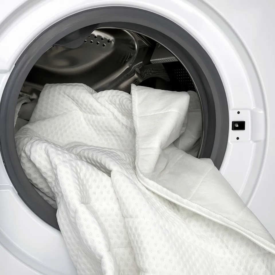 Inside of white dryer with quilted mattress pad for extra cushioning.