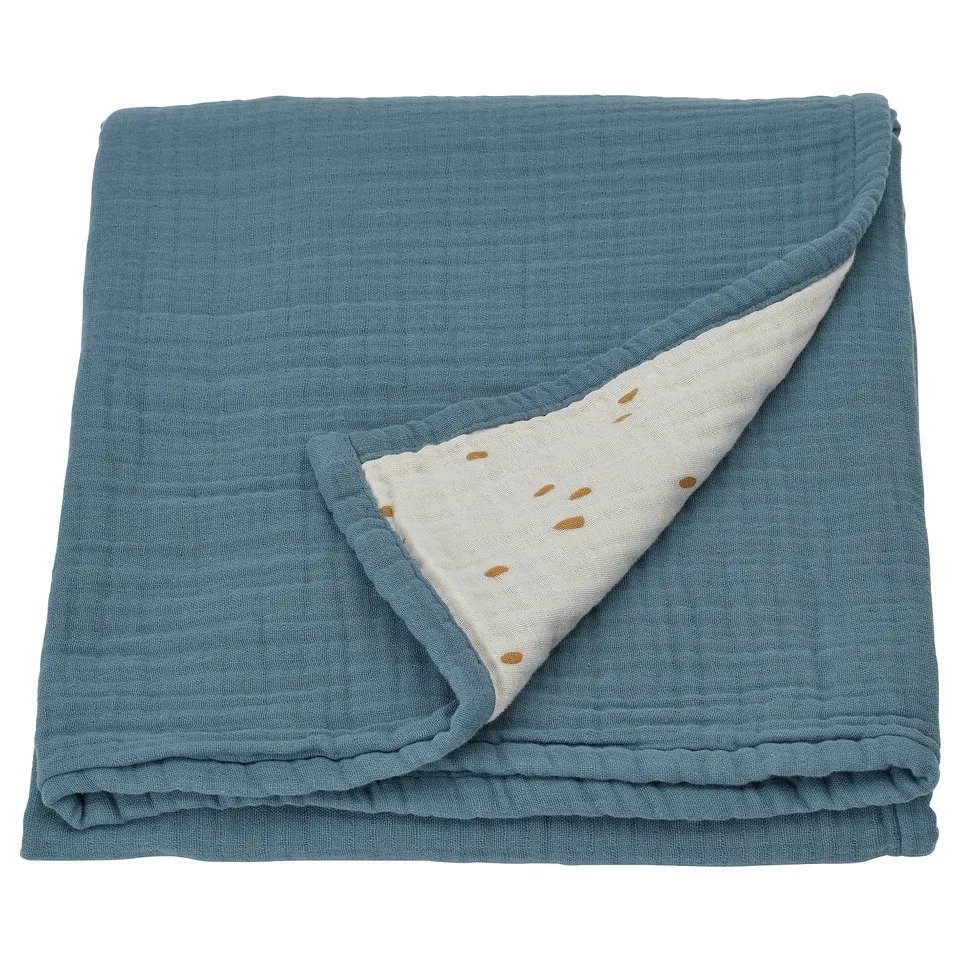 Folded blue baby blanket with white dotted side, made of organic cotton.