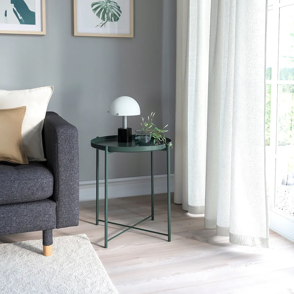 Emerald green GLADOM side table beside grey sofa, with lamp, plant, speaker; beige curtain, wall art, blue walls.
